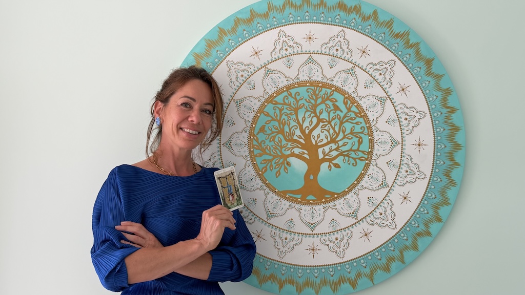 Ludivine Servan dans son cabinet du Haillan, devant un mandala de l’arbre de vie, une carte de tarot à la main